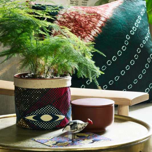 Osime Home Plant and Storage Pot with a small plant inside. Position on top of a brass finished side table.