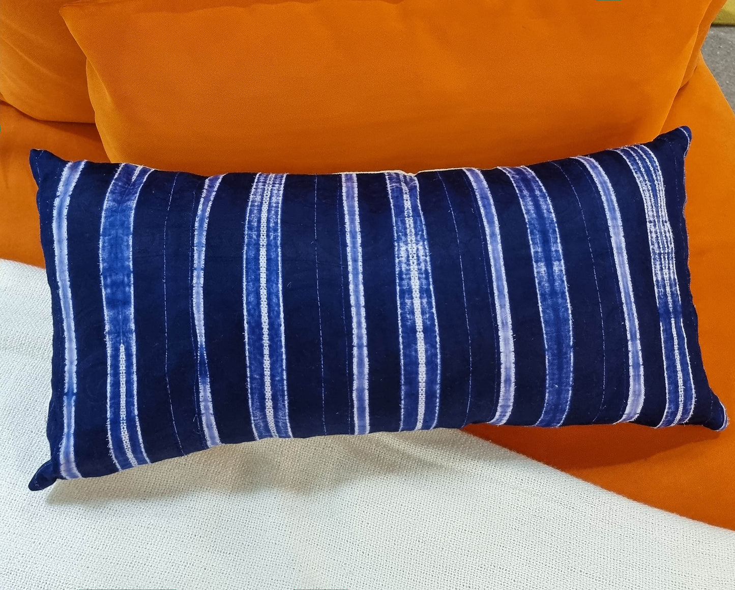Coastal Blue, white and blue stripe rectangle lumbar cushion on orange sofa chair.